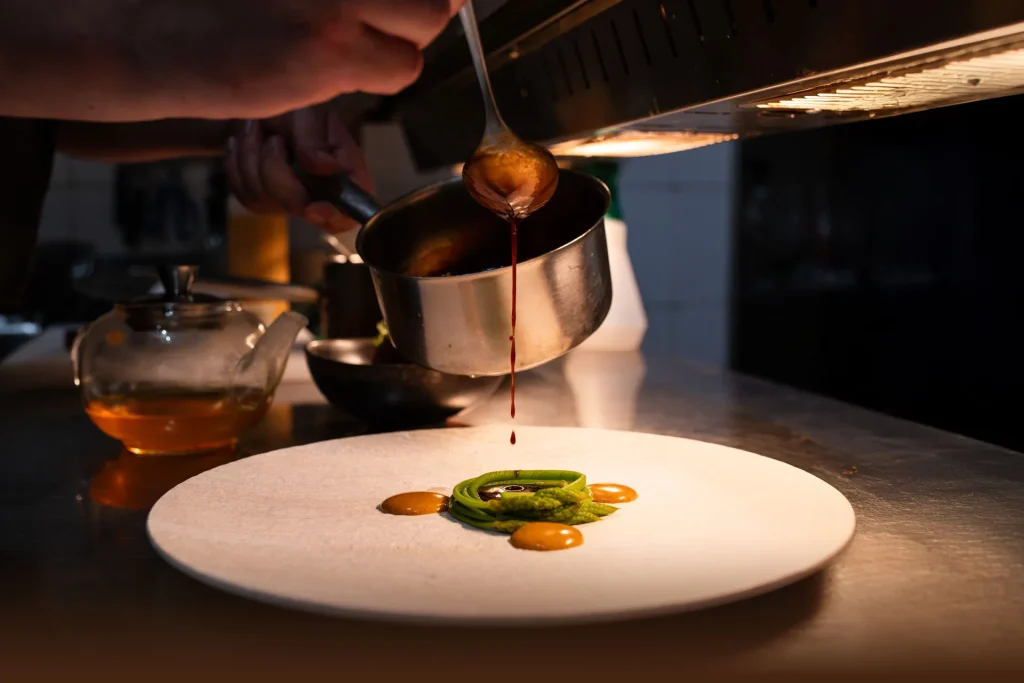 Le chef nappe de sauce une assiette dressée, en cuisine