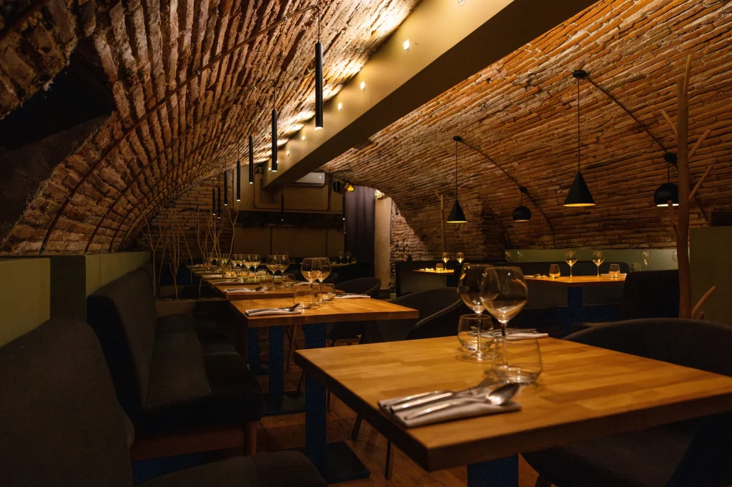 Salle voûtée en briques du restaurant L'Émulsion, tables en bois dressées