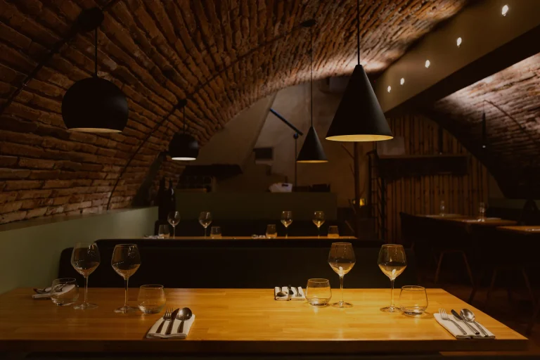 Salle voûtée aux lumières tamisées avec une grande tablée dressée