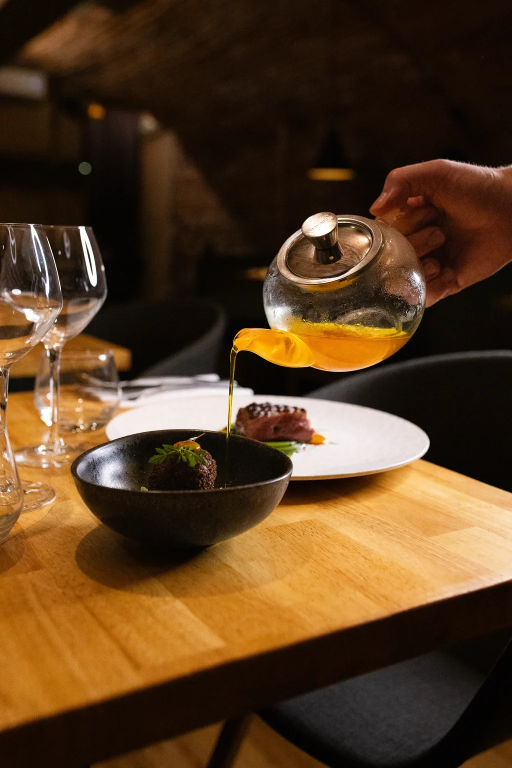 Bouillon versé à table depuis une théière en verre dans un bol noir