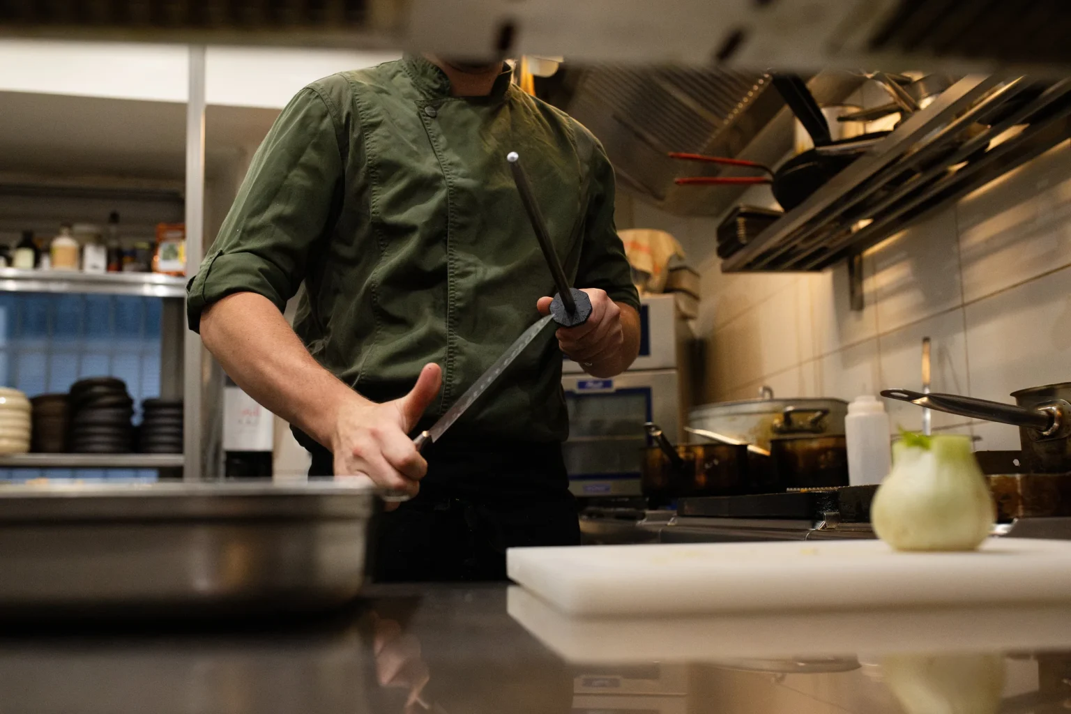 Le chef découpe un produit sur son plan de travail, en cuisine