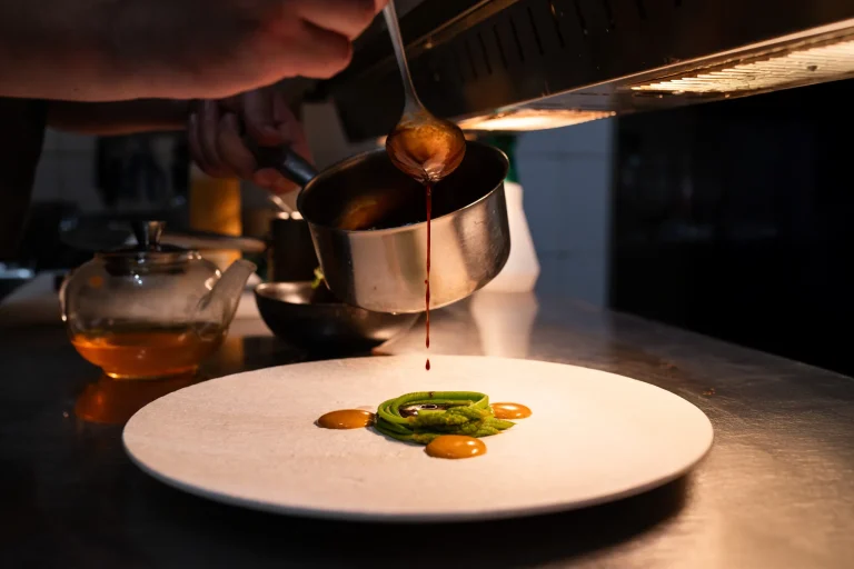 Nappage d'une sauce depuis une casserole sur une assiette dressée