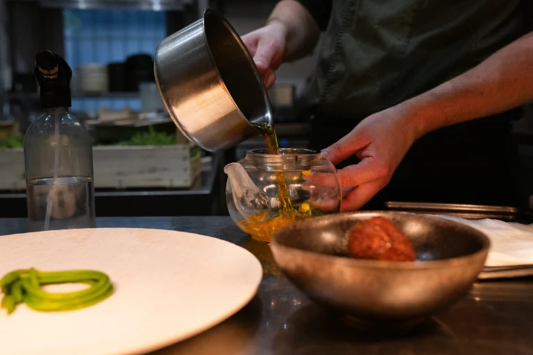 En cuisine, le bouillon est versé d'une casserole dans une théière en verre